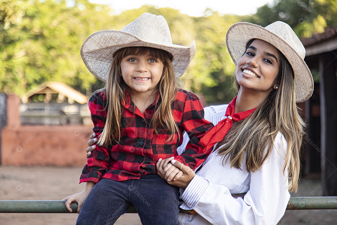 Mãe linda ao lado de sua filha sobre uma fazenda