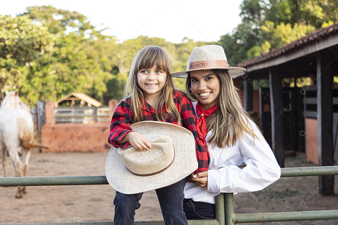 Mãe linda ao lado de sua filha sobre uma fazenda