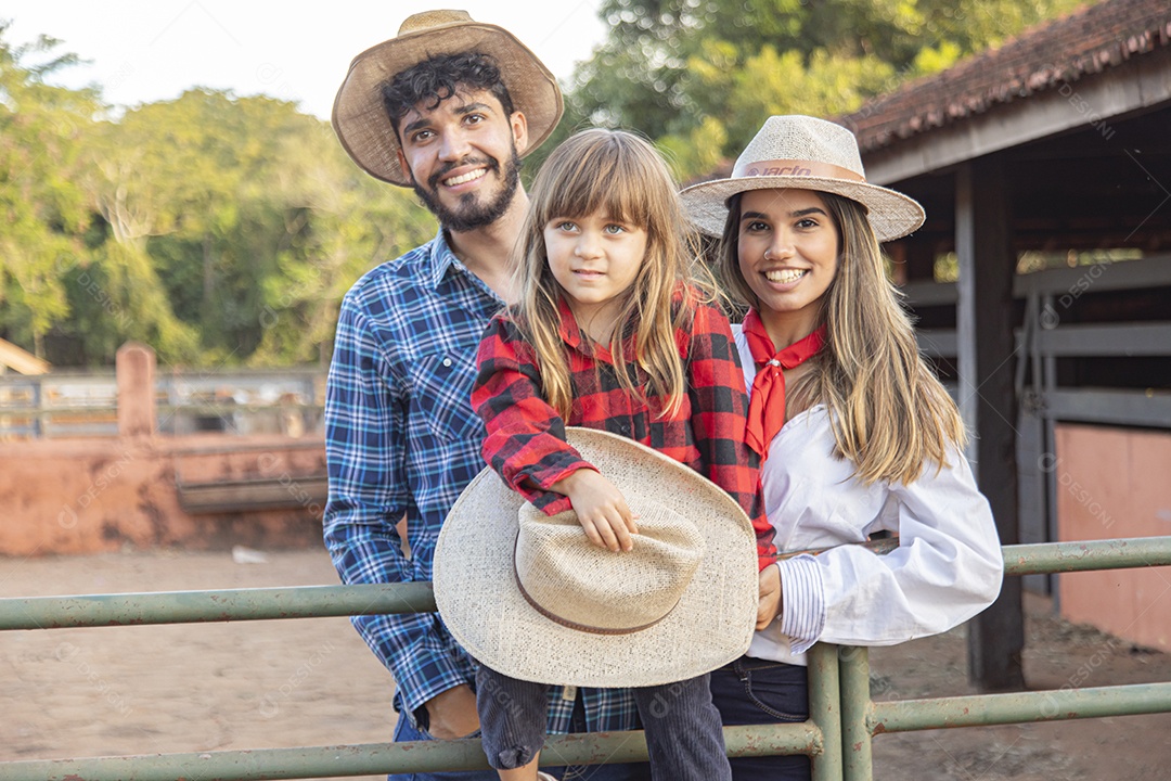 Pai e mãe ao lado de sua filha sobre uma fazenda