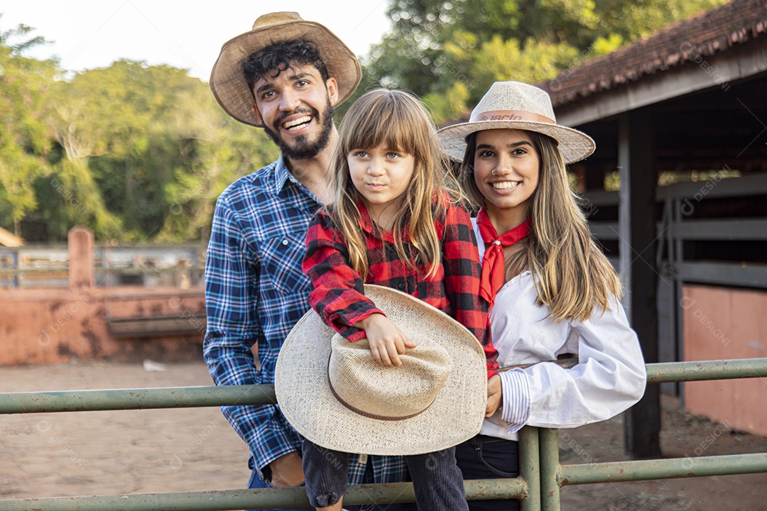 Pai e mãe ao lado de sua filha sobre uma fazenda