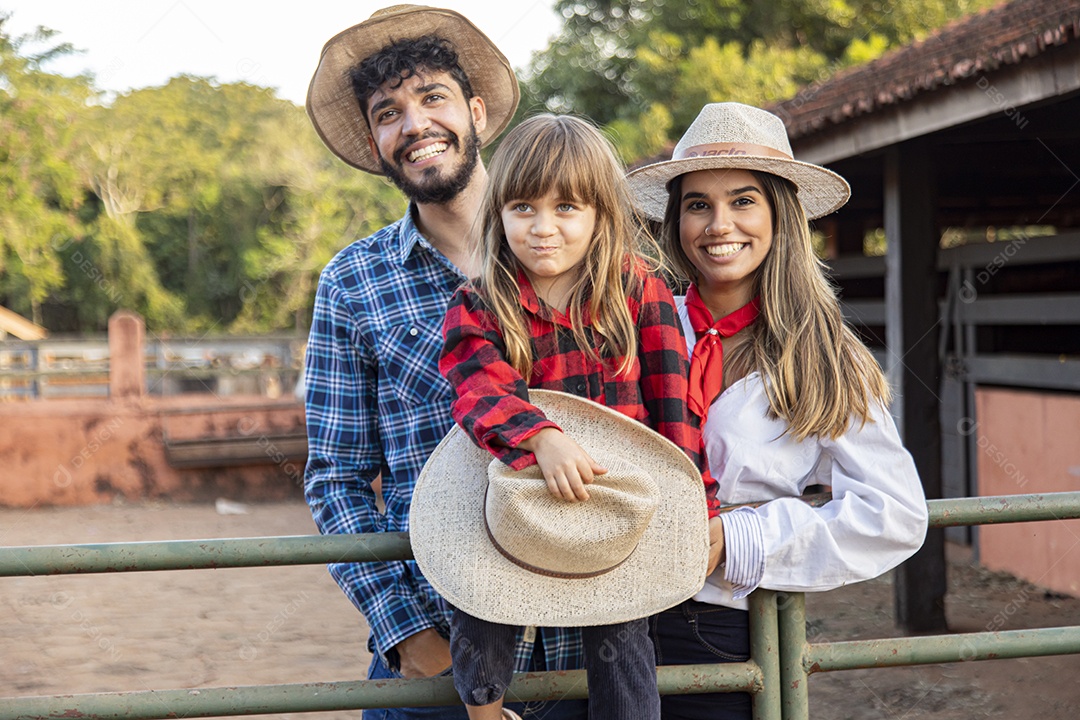 Pai e mãe ao lado de sua filha sobre uma fazenda