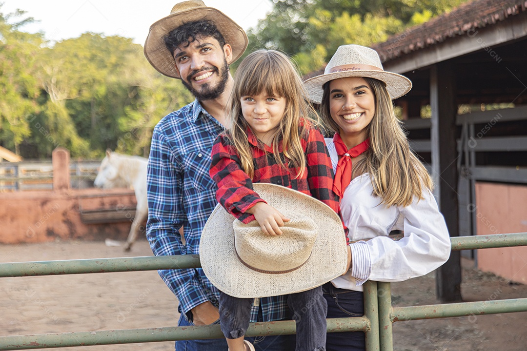 Pai e mãe ao lado de sua filha sobre uma fazenda