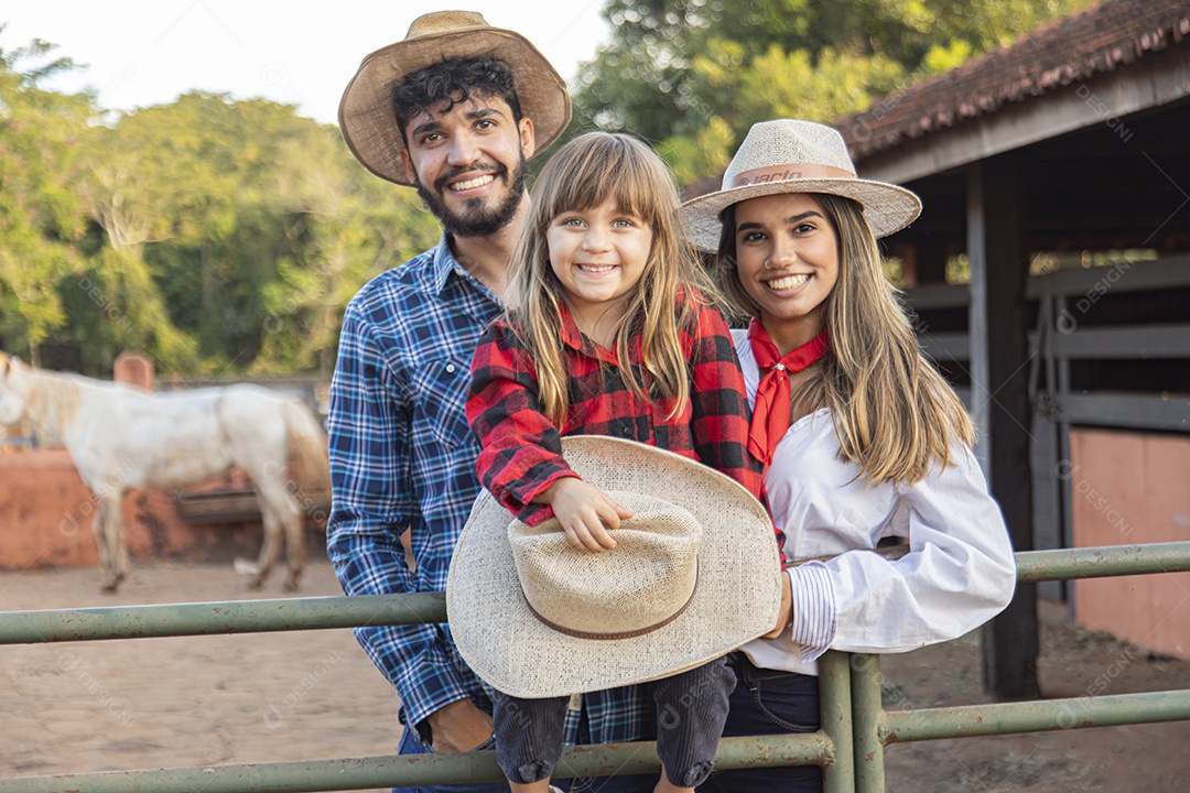 Pai e mãe ao lado de sua filha sobre uma fazenda