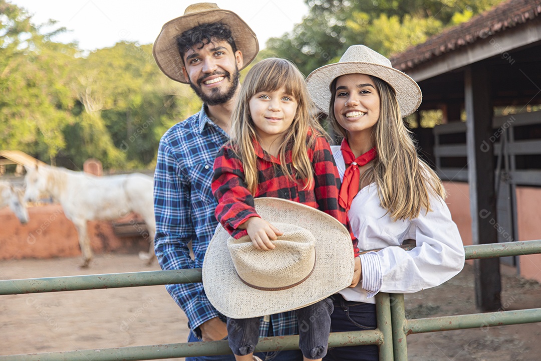 Pai e mãe ao lado de sua filha sobre uma fazenda