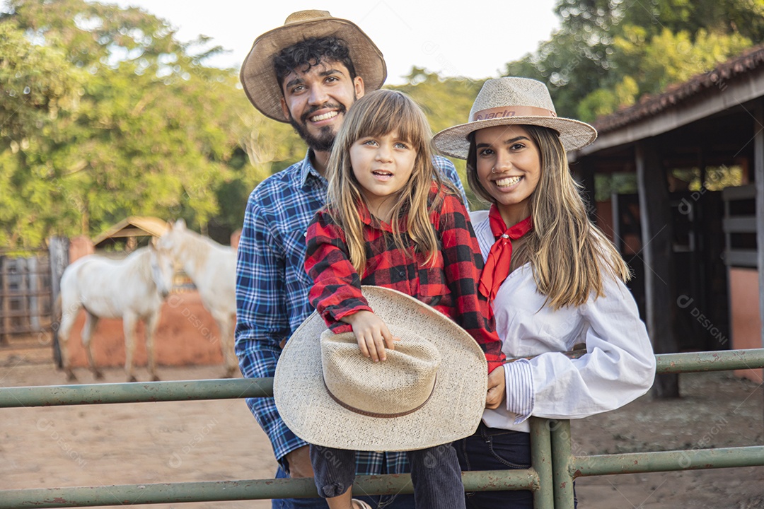 Pai e mãe ao lado de sua filha sobre uma fazenda
