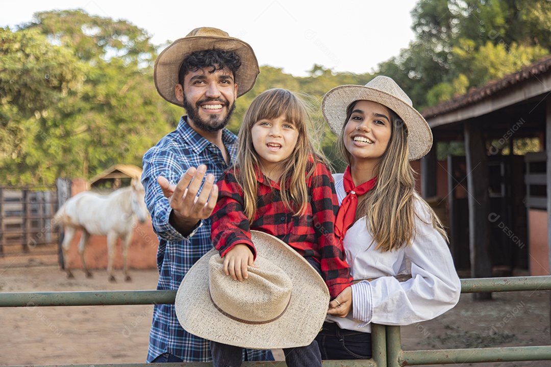 Pai e mãe ao lado de sua filha sobre uma fazenda