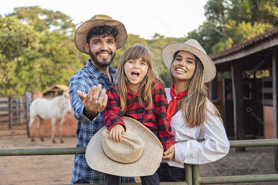 Pai e mãe ao lado de sua filha sobre uma fazenda