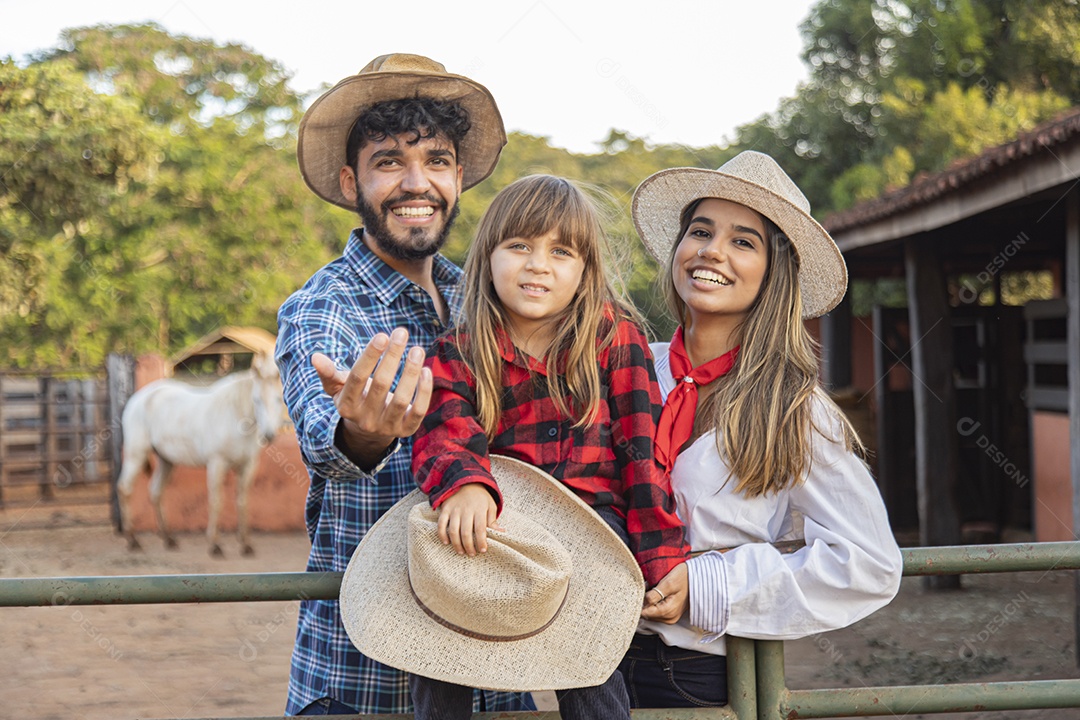 Pai e mãe ao lado de sua filha sobre uma fazenda