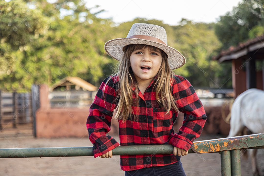 Menina feliz e sorridente sobre uma fazenda