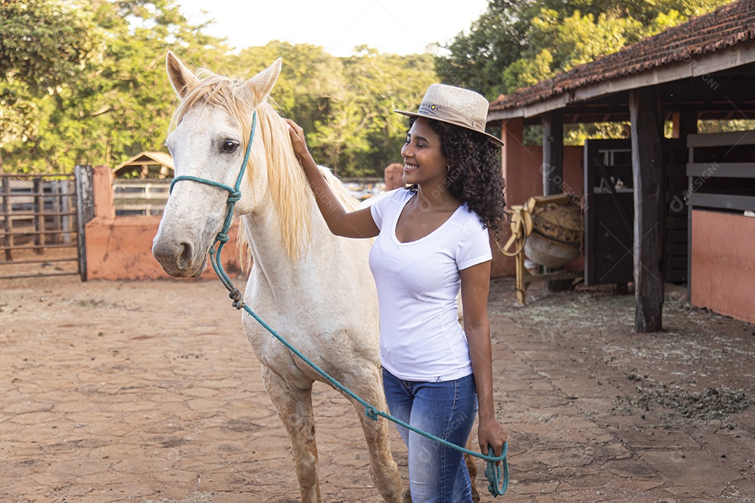 Menina jovem sobre uma fazenda ao lado de seu cavalo