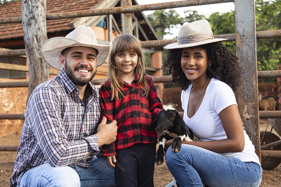 Pai e mãe agricultores ao lado de sua filha sobre uma fazenda