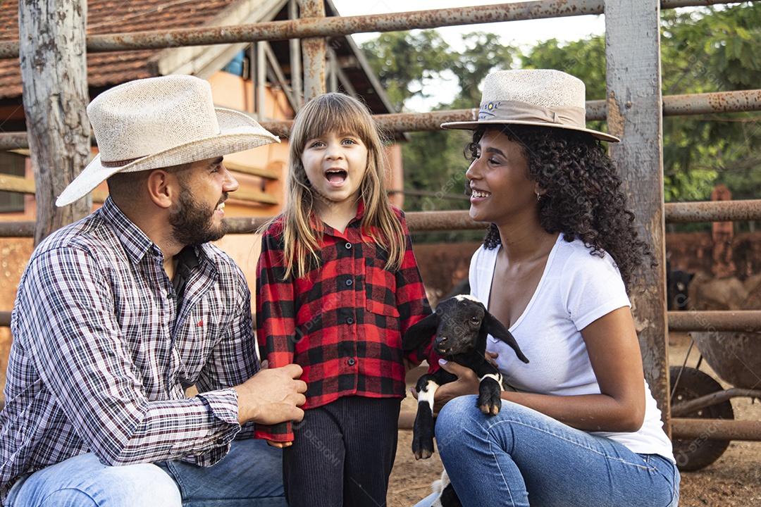 Pai e mãe agricultores ao lado de sua filha sobre uma fazenda