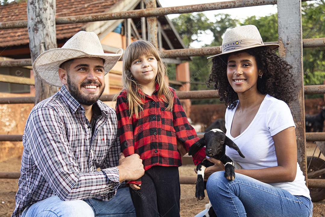 Pai e mãe agricultores ao lado de sua filha sobre uma fazenda