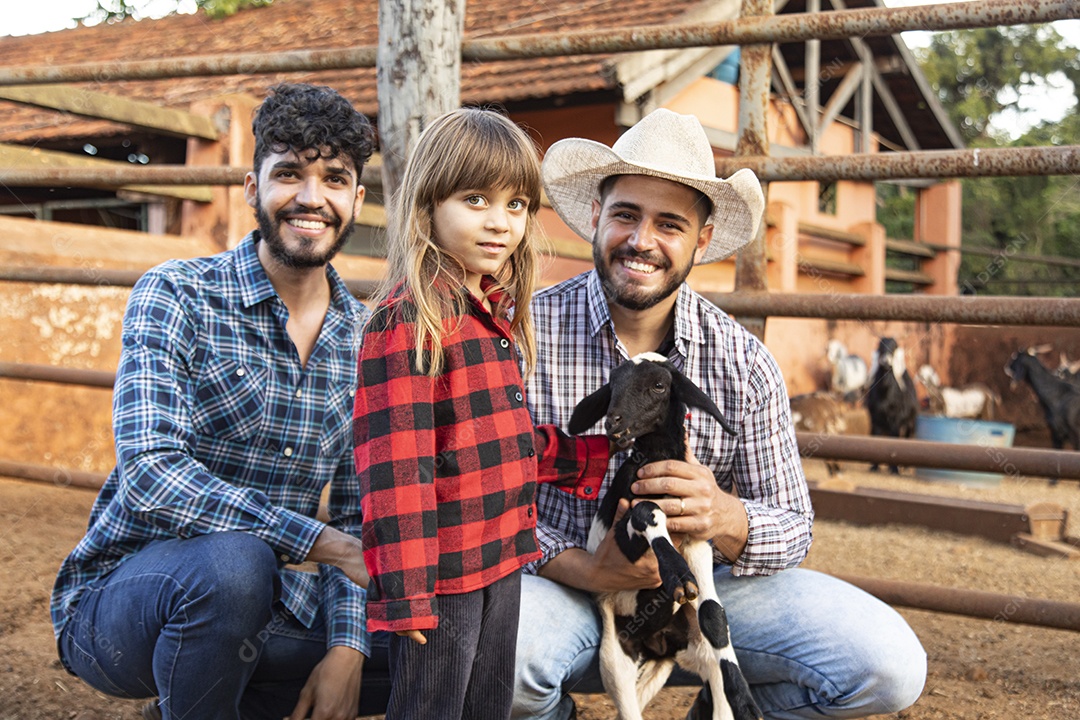 Homens jovens agricultores ao lado uma linda garotinha sobre uma fazenda