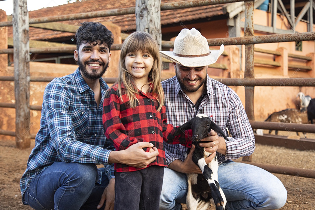 Homens jovens agricultores ao lado uma linda garotinha sobre uma fazenda