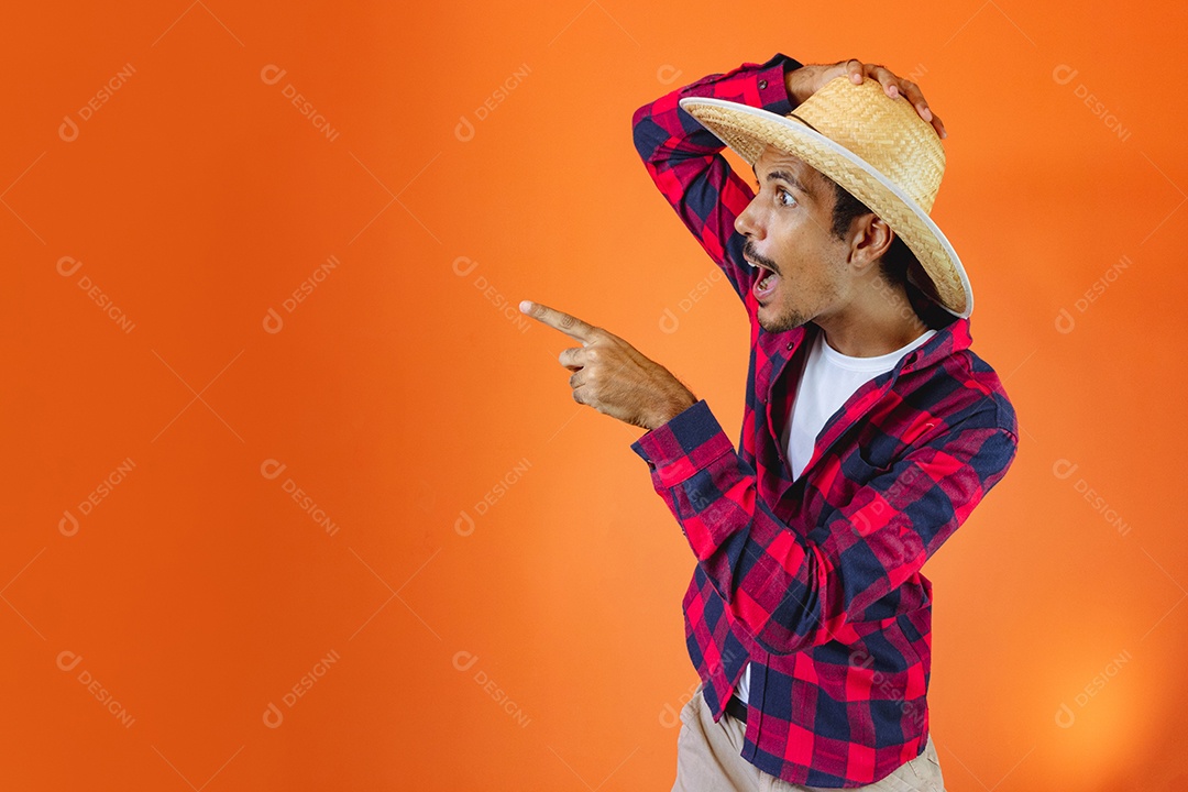 Festa Junina. Homem negro com roupa segurando um celular isolado em fundo laranja.