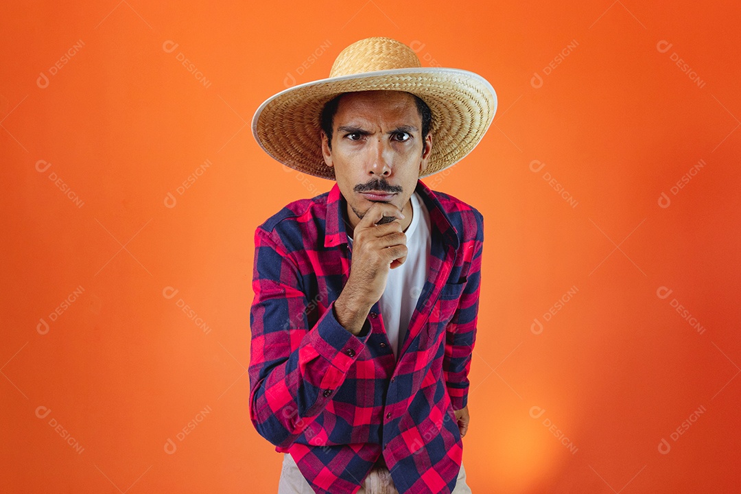 Festa Junina. Homem negro com roupa segurando um celular isolado em fundo laranja.