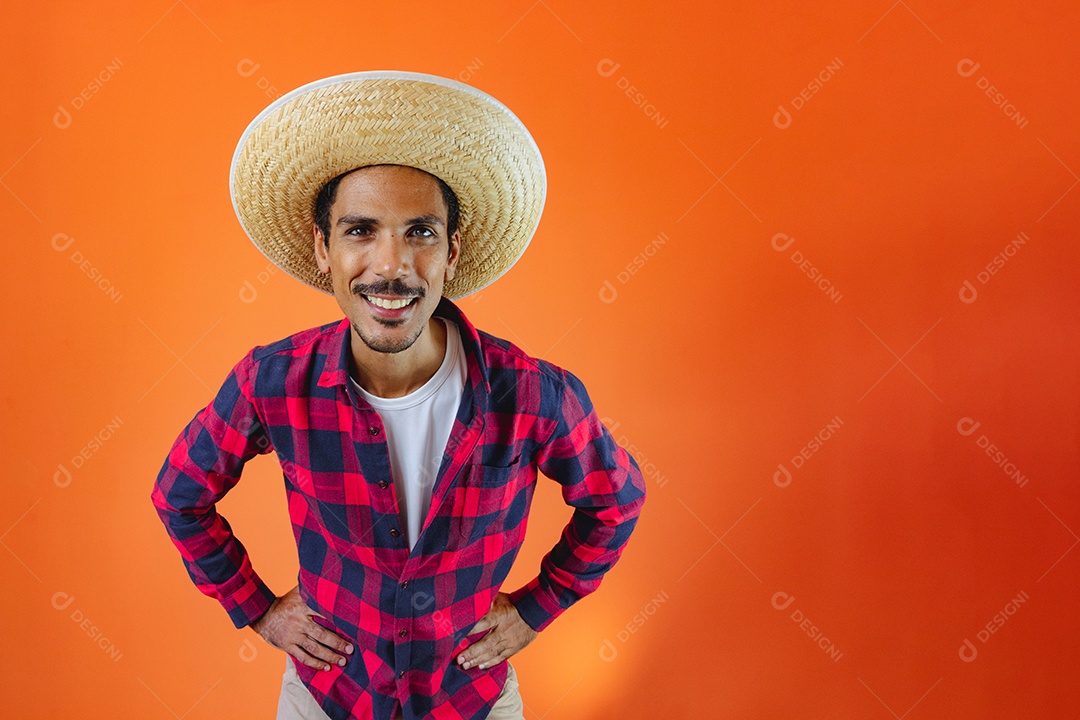 Festa Junina. Homem negro com roupa segurando um celular isolado em fundo laranja.