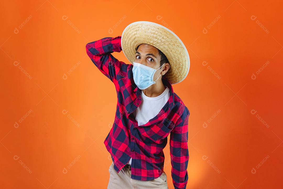 Festa Junina. Homem negro com roupa segurando um celular isolado em fundo laranja.