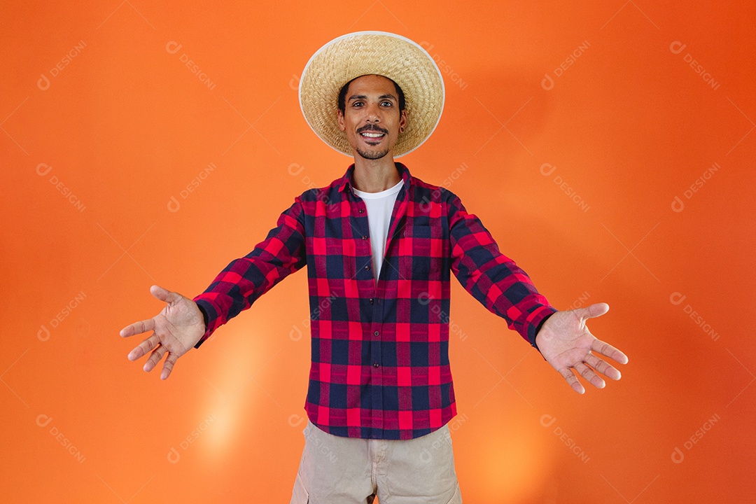 Festa Junina. Homem negro com roupa segurando um celular isolado em fundo laranja.
