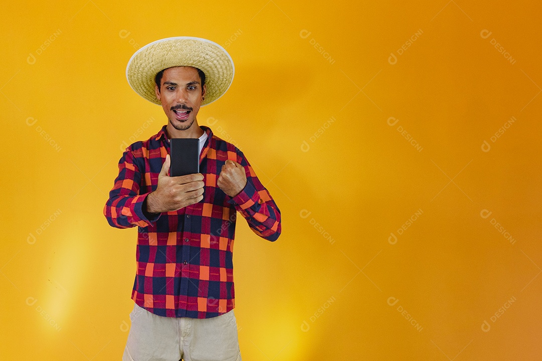 Homem negro vestindo roupas tradicionais para a Festa Junina isolada em fundo amarelo