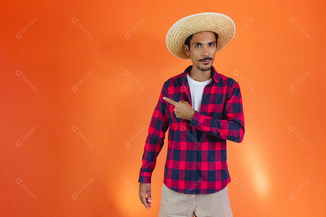 Festa Junina. Homem negro com roupa apontando isolado em fundo laranja.