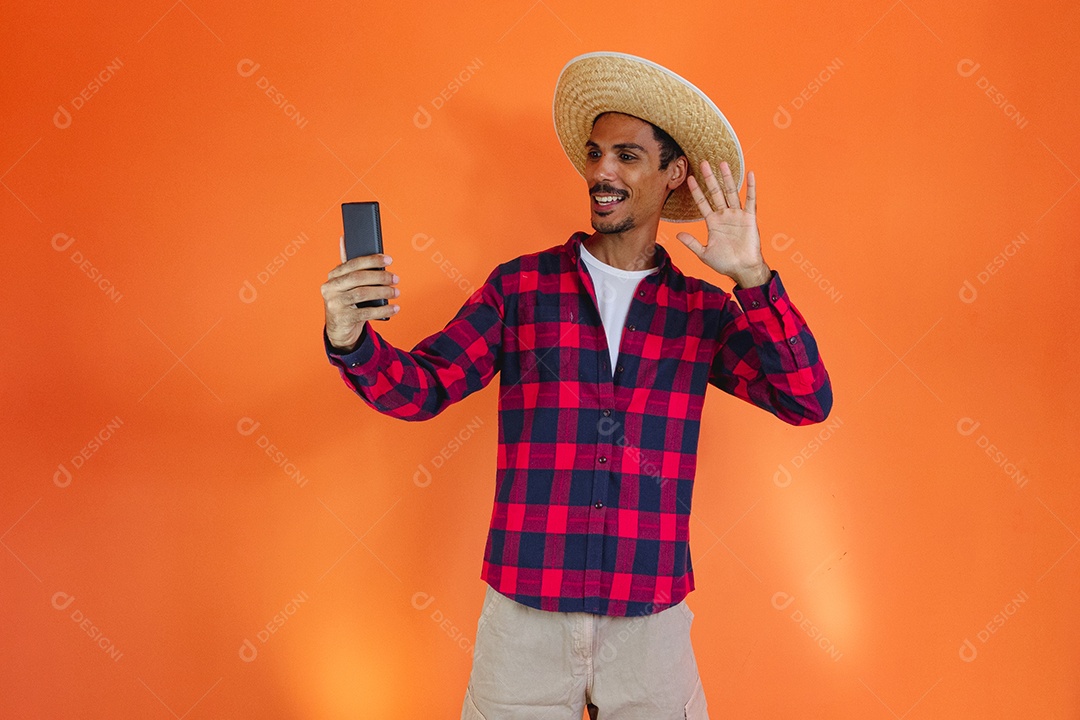 Festa Junina. Homem negro com roupa apontando isolado em fundo laranja.