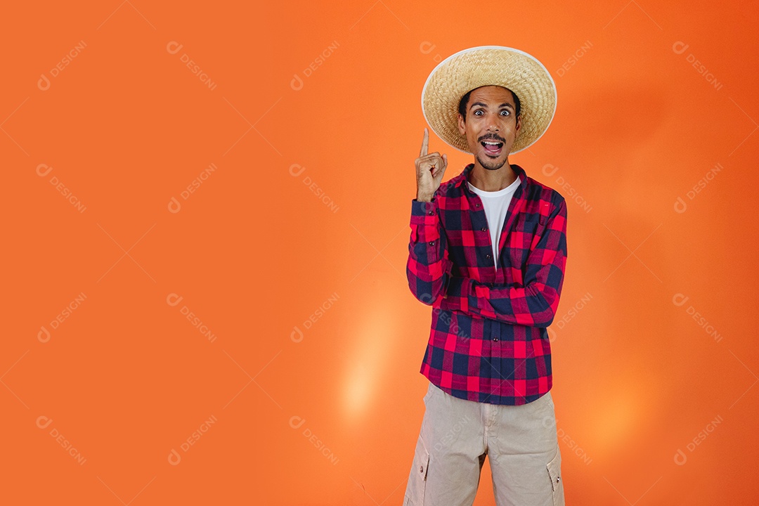 Festa Junina. Homem negro com roupa apontando isolado em fundo laranja.