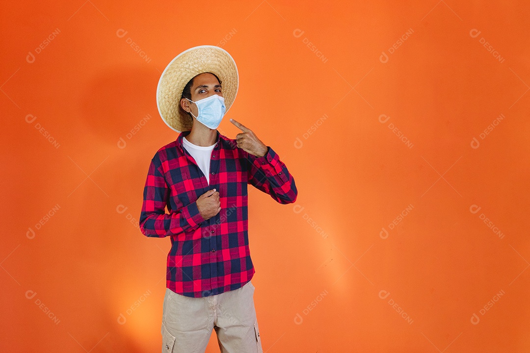 Festa Junina. Homem negro com roupa apontando isolado em fundo laranja.