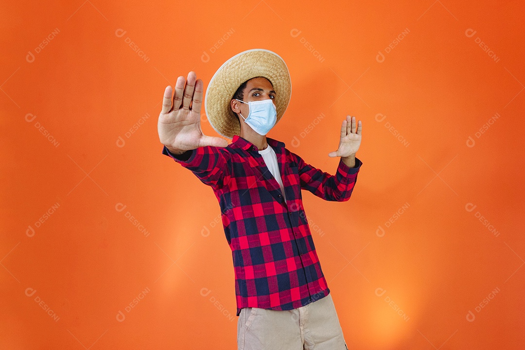 Festa Junina. Homem negro com roupa apontando isolado em fundo laranja.