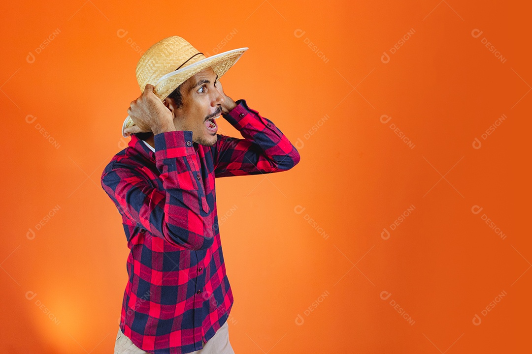 Festa Junina. Homem negro com roupa apontando isolado em fundo laranja.