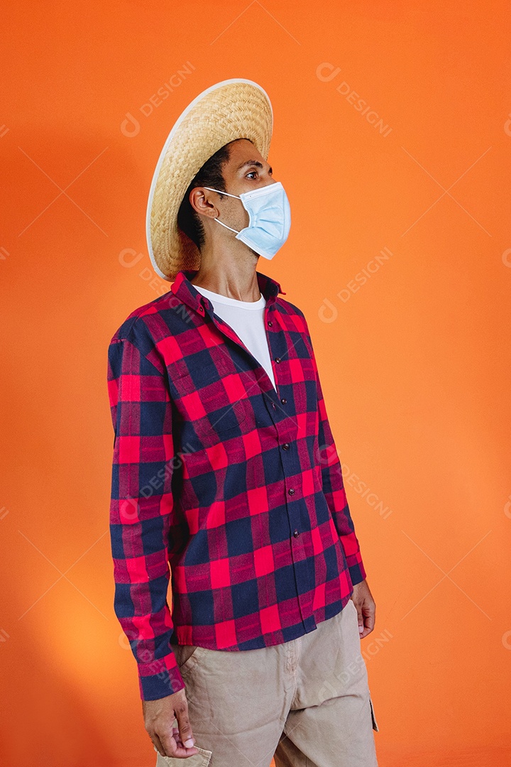 Festa Junina. Homem negro com roupa apontando isolado em fundo laranja.