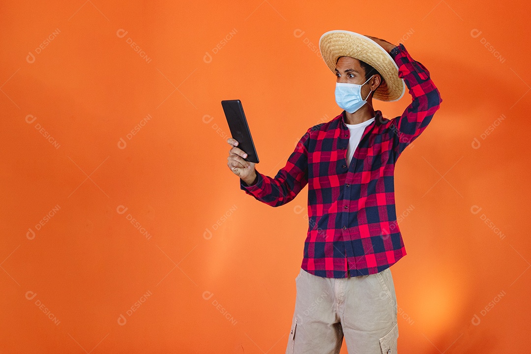 Festa Junina. Homem negro com roupa apontando isolado em fundo laranja.