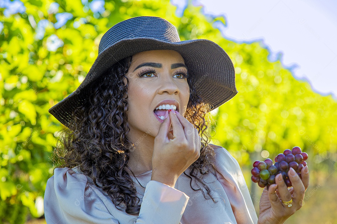 Mulher jovem sobre plantio de uvas