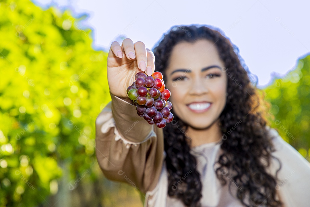 Mulher jovem sobre plantio de uvas