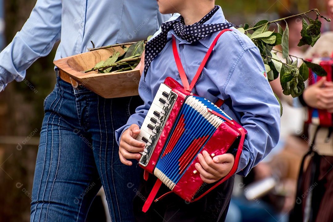Menino ao lado da mãe passando em desfile com gaita na mão