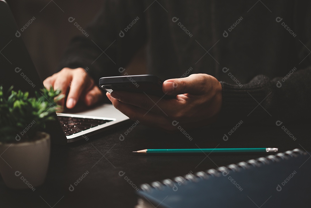 homem usando telefone inteligente móvel e trabalhando em laptop computer