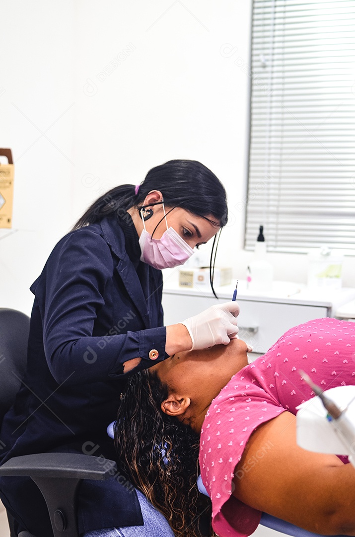 Dentista sobre seu consultorio odontológico atendendo seu paciente