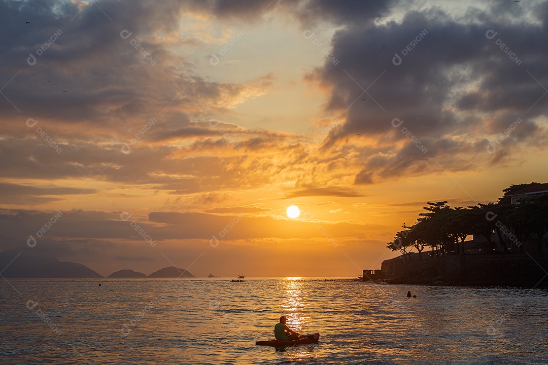 silhuetas de pessoas em canoas ao amanhecer na praia de Copacabana, no Rio de Janeiro