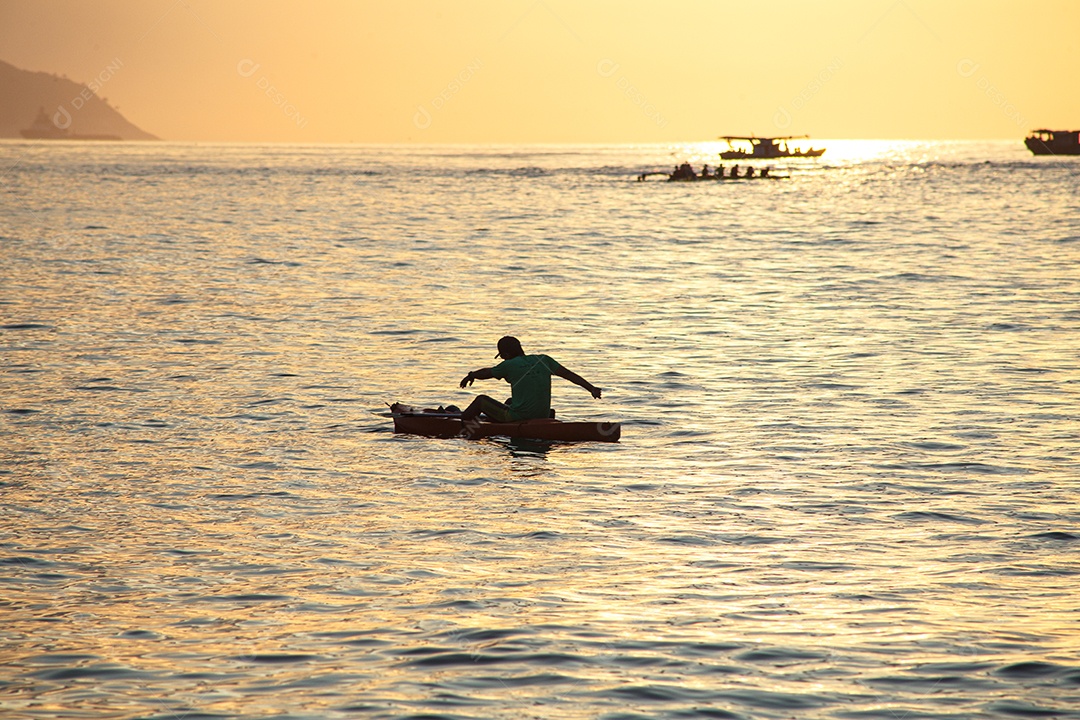 silhuetas de pessoas em canoas ao amanhecer na praia de Copacabana, no Rio de Janeiro