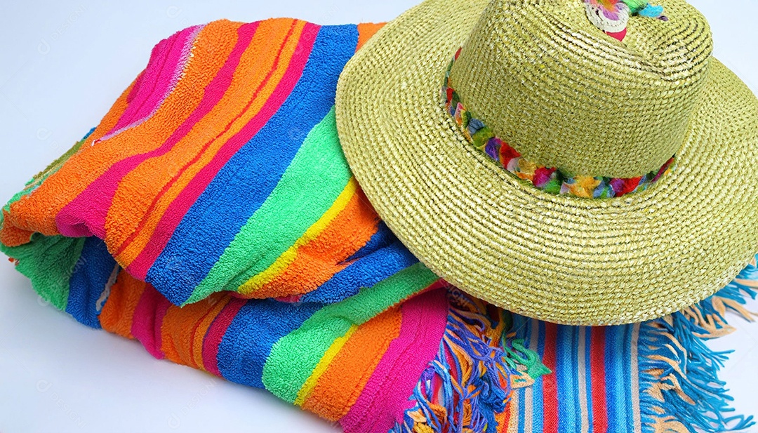 Chapéu colorido e toalha na areia da praia