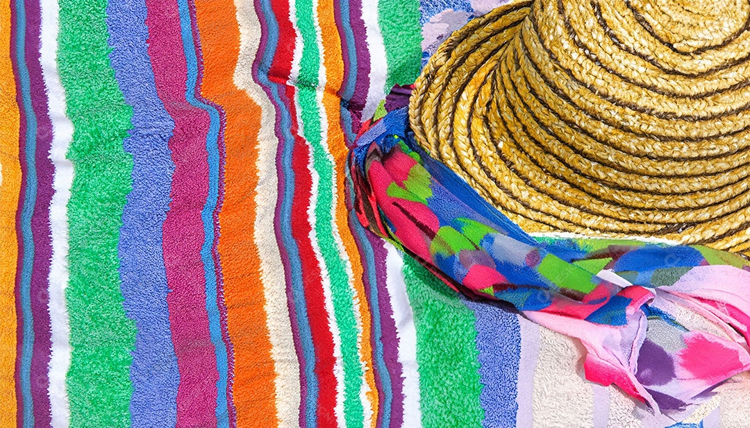 Chapéu colorido e toalha na areia da praia