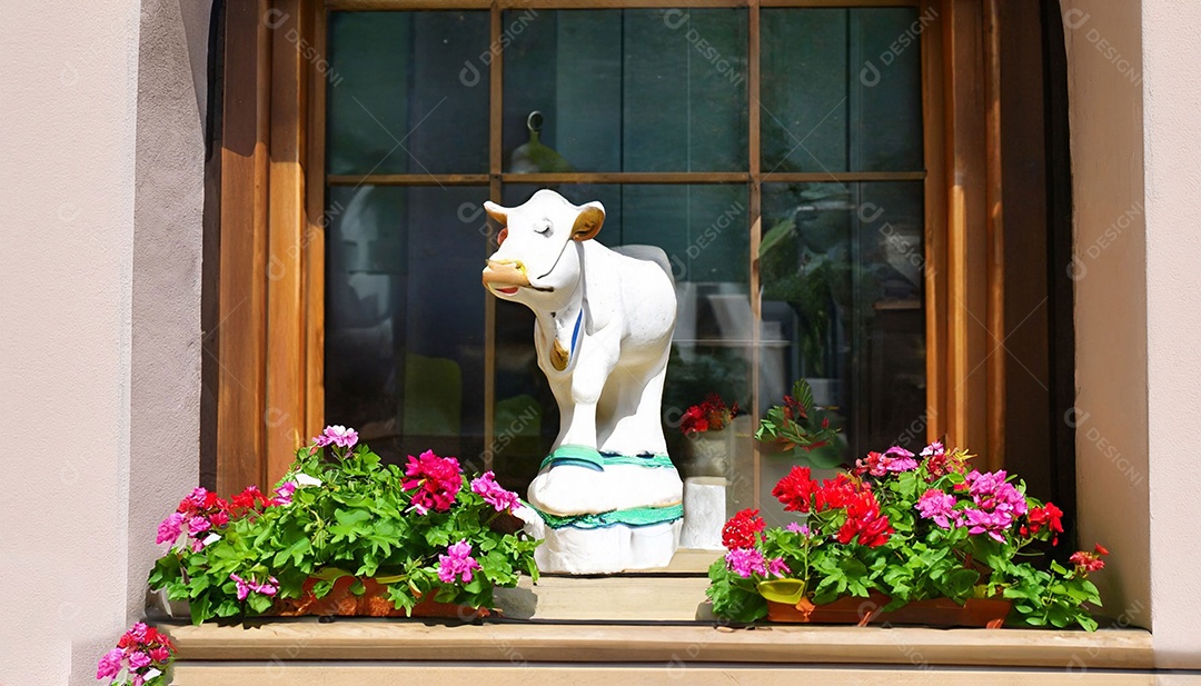 Escultura de vaca na janela com vasos de flores