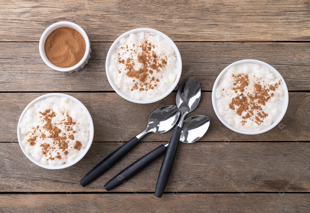 Canjica ou munguza, típico creme doce de milho branco brasileiro com canela sobre mesa de madeira.
