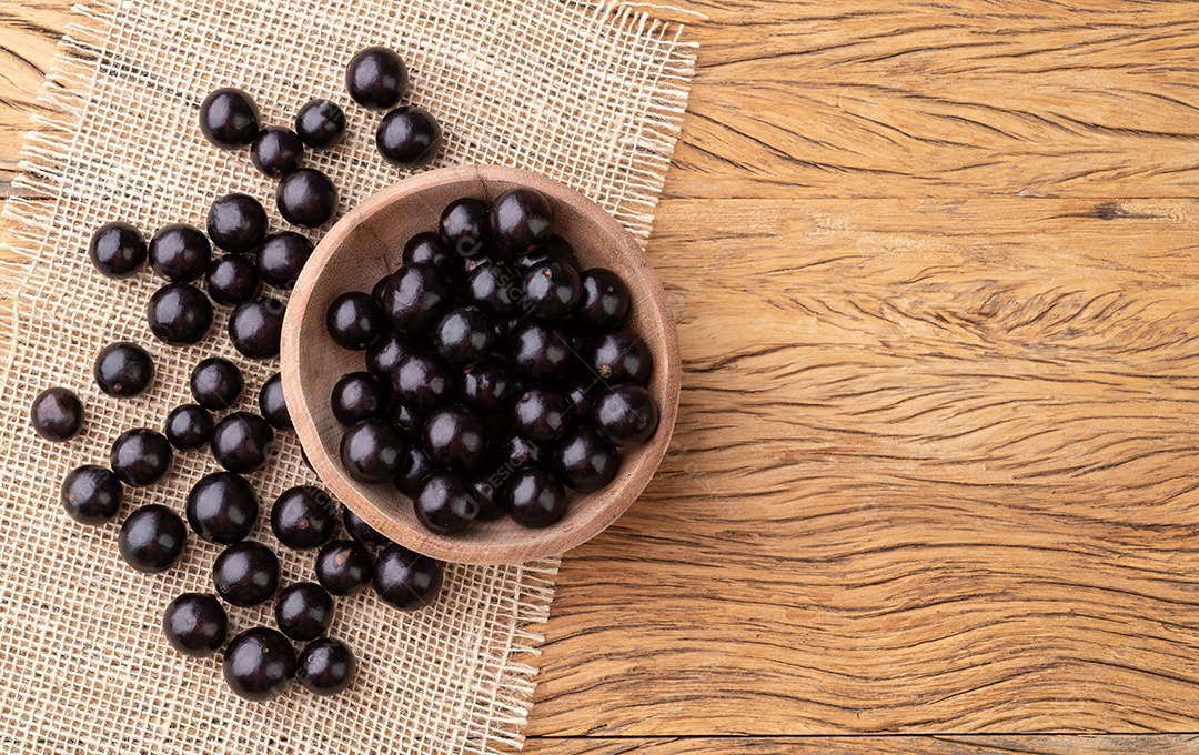 Jabuticabas em uma tigela sobre mesa de madeira com espaço de cópia.