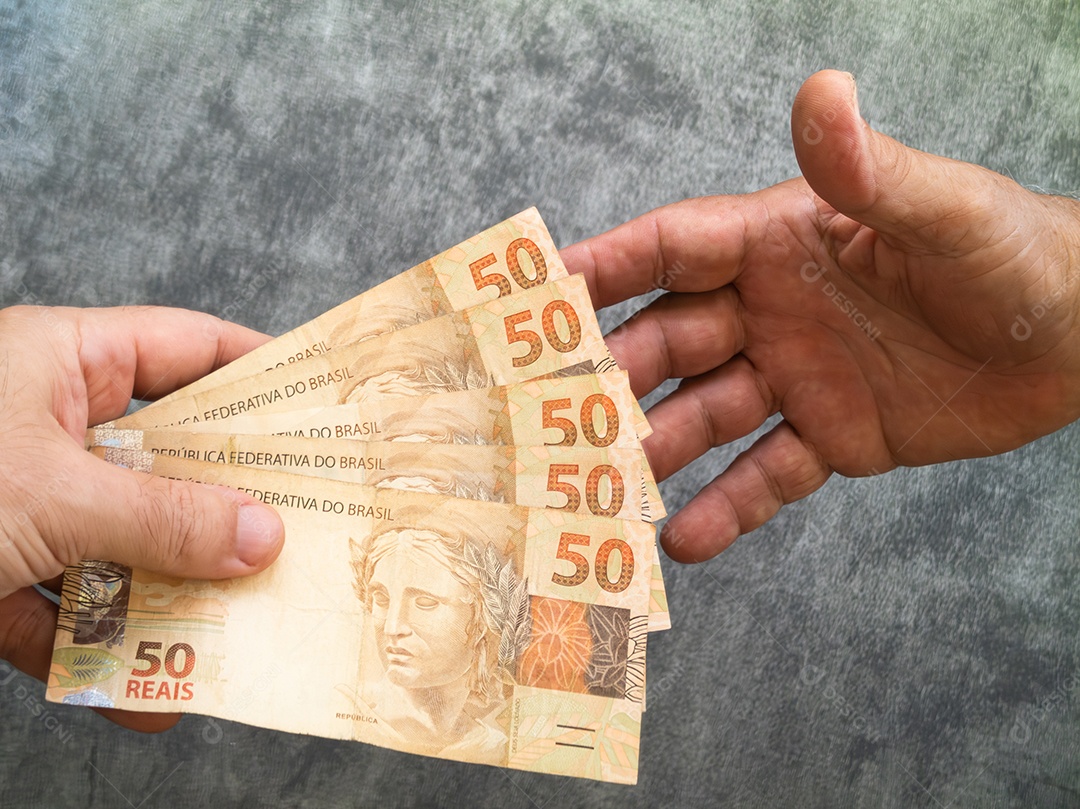 Mão segurando cédulas de cinquenta reais. dinheiro brasileiro.