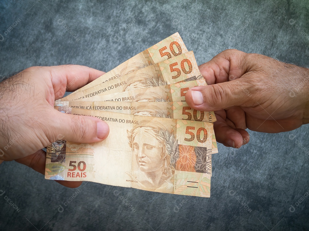 Mão segurando cédulas de cinquenta reais. dinheiro brasileiro.