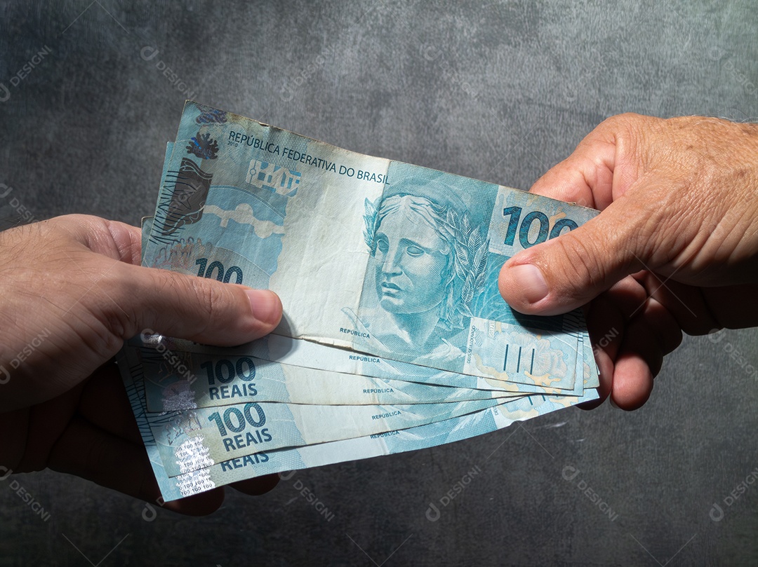 Mão segurando notas de cem reais brasileiras. Conceito de finanças.