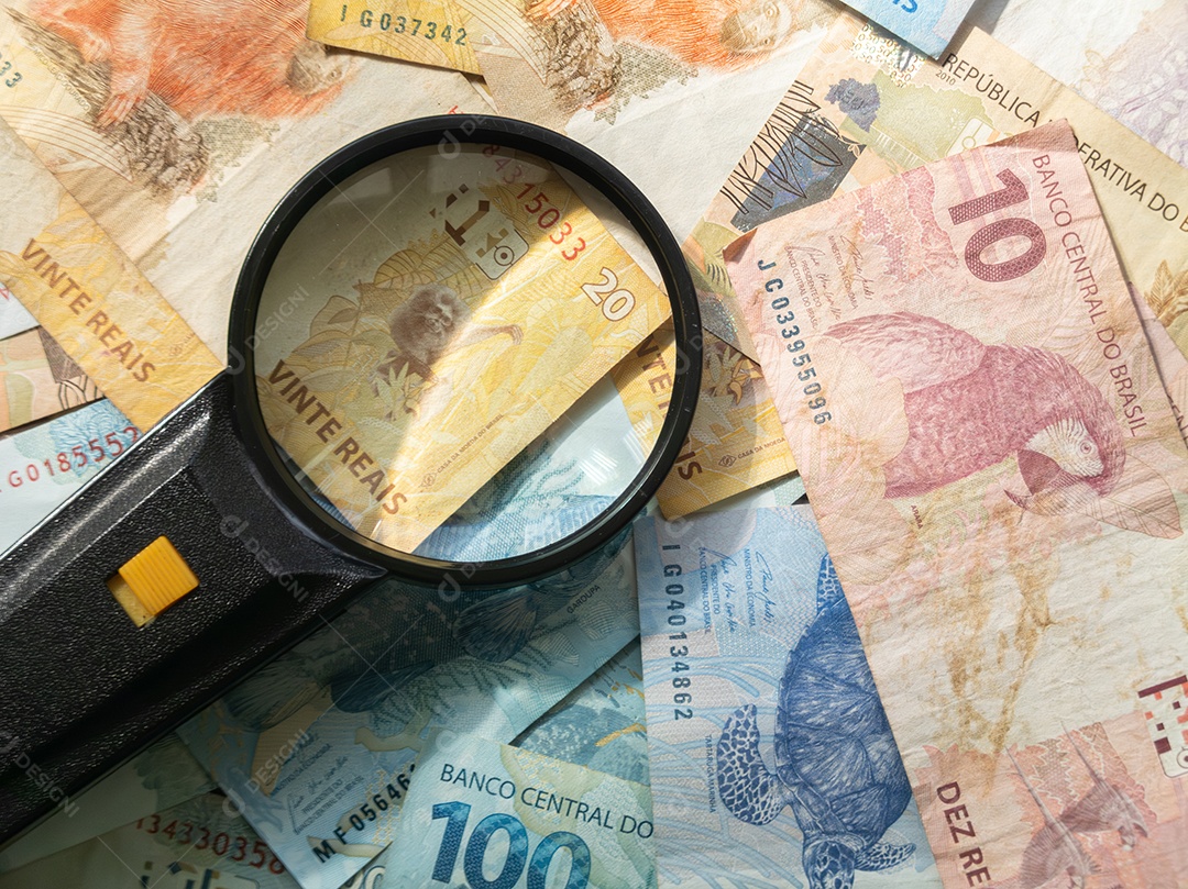 Lupa sobre cédulas de dinheiro brasileiro. Conceito de finanças.