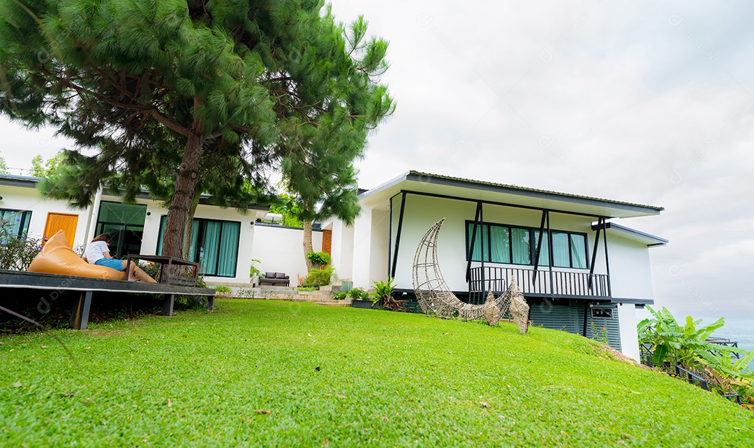 Vista externa da casa branca na colina com árvores e gramado verde